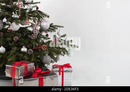 Weihnachtsbaum mit drei Geschenken darunter. Geschenkschachteln in Silber-Weiß-Rot Stockfoto