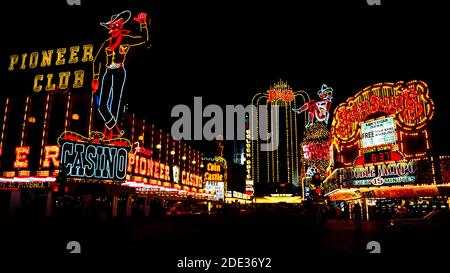 Neon und andere bunte Lichter machten diese Outdoor-Schilder für Casinos und Hotels in der Nacht und während des Tages an der Fremont Street, dem ursprünglichen Stadtzentrum für Glücksspiel und gute Zeiten in Las Vegas, Nevada, USA, hervorstechen. Leicht zu erkennen in der Neon-Anzeige sind ein Cowboy und ein Cowgirl mit dem Spitznamen Vegas Vic und Vegas Vickie. Seit der Aufnahme dieses historischen Fotos im Jahr 1983 wurde die Fremont Street mit einem Baldachin bedeckt, das die längste Videowand der Welt ist und Besuchern in der Fußgängerzone eine Sound-and-Light-Show über dem Kopf präsentiert. Stockfoto