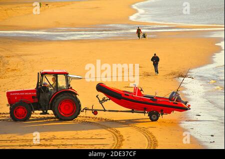 Roter Traktor startet rotes Schnellboot am Strand von St Annes Stockfoto