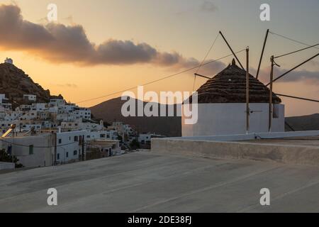 Chora, iOS Insel Griechenland - 21. September 2020: Ikonische, traditionelle Windmühlen auf dem Hauptplatz von Chora. Gelber Sonnenuntergang. Stockfoto