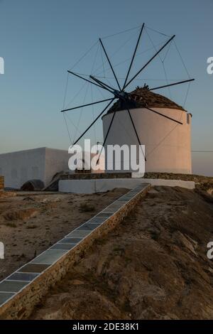 Chora, iOS Insel Griechenland - 21. September 2020: Ikonische, traditionelle Windmühlen auf dem Hauptplatz von Chora. Gelber Sonnenuntergang. Stockfoto