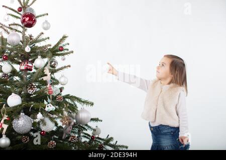 Ein Kleinkind Mädchen zeigt auf die Spitze der Weihnachten Baum Stockfoto