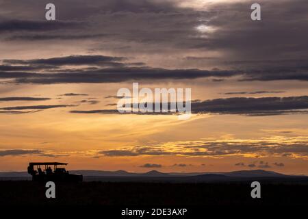 Afrika, Kenia, Northern Serengeti Plains, Maasai Mara. Mara Sonnenaufgang mit Safari Jeep Silhouette. Stockfoto