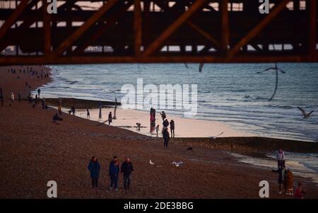 Brighton UK 28. November 2020 - Besucher genießen den Sonnenuntergang am Strand von Brighton und am Meer, während ein schöner warmer Herbsttag an der Südküste zu Ende geht : Credit Simon Dack / Alamy Live News Stockfoto