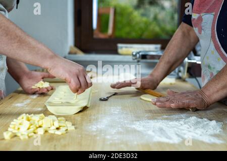 Nahaufnahme der Hände der Frau, die den Teig bearbeiten, um Käseravioli zuzubereiten. Traditionelle sardische Küche. Stockfoto