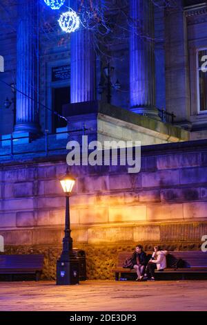 Ein junges Paar, das draußen unter Nacht im Harris sitzt Museum und Bibliothek in Preston Stockfoto