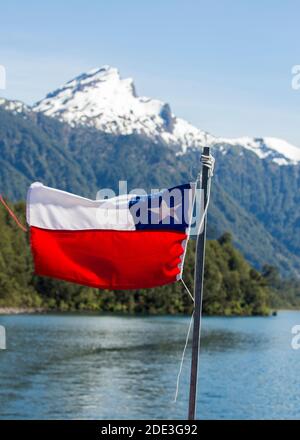 Die chilenische Flagge auf einer Fähre zwischen Chile und Argentinien auf dem Lago Todos Los Santos, Petrohue, Chile, mit schneebedeckten Vulkan in der Ferne Stockfoto