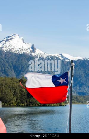 Die chilenische Flagge auf einer Fähre zwischen Chile und Argentinien auf dem Lago Todos Los Santos, Petrohue, Chile, mit schneebedeckten Vulkan in der Ferne Stockfoto