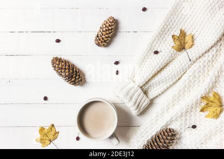 Herbst oder Winter Zusammensetzung. Tasse Kaffee, Frauen Mode Pullover, Kieferkegel und Herbstblätter auf weißem Holzhintergrund. Flach liegend, Draufsicht, Kopie sp Stockfoto