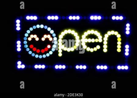 LED-Schild mit einem Smiley-Gesicht in einem lokalen Geschäftsfenster öffnen. Stockfoto