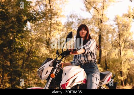 Selbstbewusste junge Frau Motorrad Reiten inmitten von Bäumen im Wald Stockfoto