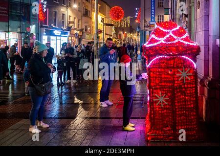 Cork, Irland. November 2020. Das Stadtzentrum von Cork war an diesem Abend sehr voll mit Familien, die sich die Weihnachtsbeleuchtung ansehen und anderen, die Getränke zum Mitnehmen kaufen. Viele Kinder posteten ihre Weihnachtsmannbriefe in den speziellen Briefkasten vor der Post. Quelle: AG News/Alamy Live News Stockfoto