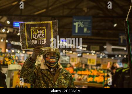 Ein Protestant mit einem Plakat, auf dem steht: "Black Lives Matter" während der Demonstration der Tod des 40-jährigen João Alberto Silveira, eines schwarzen Mannes, der am 19. November in Porto Alegre, Brasilien, von Carrefour Vigilanten brutal geschlagen wurde, hat eine Protestwelle in mehreren brasilianischen Städten ausgelöst. In Barcelona machen antirassistische Gruppen vor dem Carrefour auf Las Ramblas einen Akt der Ablehnung. Stockfoto