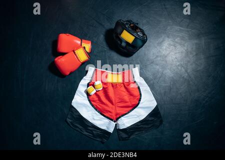 Draufsicht auf Boxhandschuhe, Shorts, Helm und Bandage Tape auf schwarzem Hintergrund Stockfoto