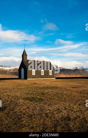 Schwarze hölzerne Budakirkja Kirche gegen schneebedeckte Berge, Budir, Snaefellsness Halbinsel, Island Stockfoto