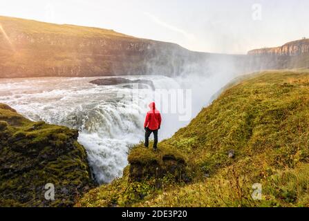 Rückansicht des männlichen Forschers bewundern Wasserfall im Hochland an Sonnenuntergang im Sommer Stockfoto