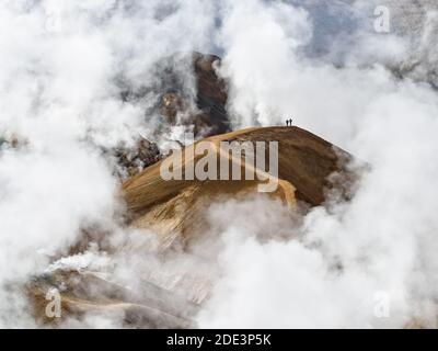 Erstaunliche abgelegene Aussicht auf Wanderer zu Fuß auf Bergkette umgeben Durch dicke Wolken Stockfoto