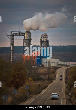 Holzfabrik mit Rauch und Straße mit Autos Stockfoto