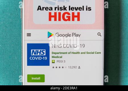 Ein Smartphone zeigt den Google Play-Bildschirm für die NHS covid-19 App für die Verwendung in Großbritannien und zeigt die Region Risiko ist hoch, Großbritannien Stockfoto