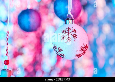 Weihnachtskugel mit roten Schneeflocken und blau glitzernden Kugelverzierungen Zum Aufhängen vor der Kamera auf farbigem Hintergrund Stockfoto