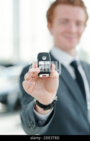Hand des jungen Managers oder Verkäufers von Fahrzeugen, die fernhalten Steuerung des Alarmsystems beim Verkauf eines neuen Fahrzeugs an einen der Clients im Auto-Center Stockfoto