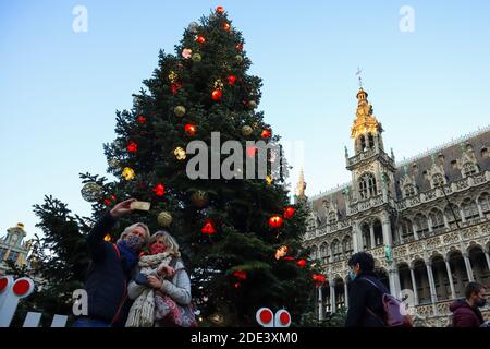 Brüssel, Belgien. November 2020. Am 28. November 2020 posieren Menschen für Fotos mit einem Weihnachtsbaum auf dem Grand Place in Brüssel, Belgien. Der Weihnachtsbaum am Grand Place von Brüssel wurde in diesem Jahr mit dem Thema "neu" dekoriert. Quelle: Zheng Huansong/Xinhua/Alamy Live News Stockfoto