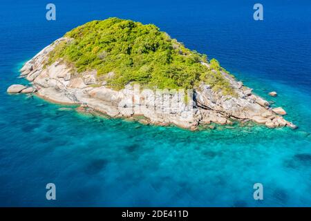 Luftdrohnenansicht einer winzigen, wunderschönen tropischen Insel, umgeben von Korallenriff und klarem Ozean. Stockfoto