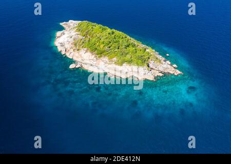 Luftdrohnenansicht einer winzigen, wunderschönen tropischen Insel, umgeben von Korallenriff und klarem Ozean. Stockfoto