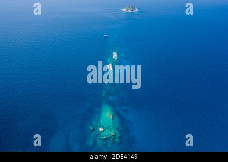 Luftaufnahme eines TAUCHBOOTES, das über einem klaren, tropischen Korallenriff auf den Similan Inseln in Thailand festgemacht ist. Stockfoto