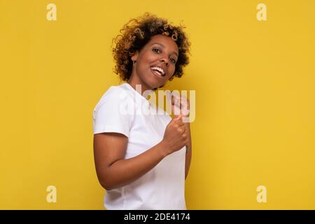 afroamerikanische junge Frau tanzt und lächelt. Studio auf rosa Wand aufgenommen. Stockfoto
