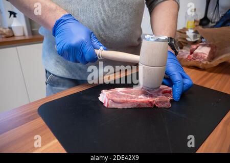 Ein Schnitzel wird mit einem Quirl weich geschlagen Stockfoto