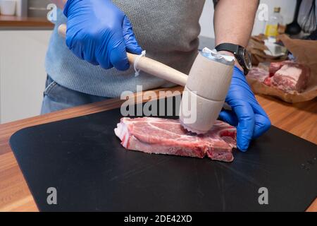 Ein Schnitzel wird mit einem Quirl weich geschlagen Stockfoto