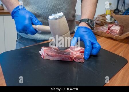 Ein Schnitzel wird mit einem Quirl weich geschlagen Stockfoto