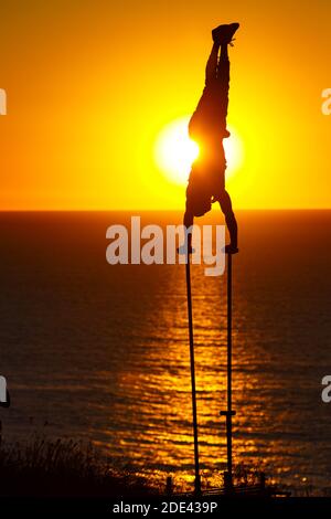 La JOLLA, KALIFORNIEN. 27. November 2020. Ein Außengymnast macht einen Handstand auf zwei Stangen, wobei die Sonne hinter ihm bei Torrey Pines Gliderport A untergeht Stockfoto