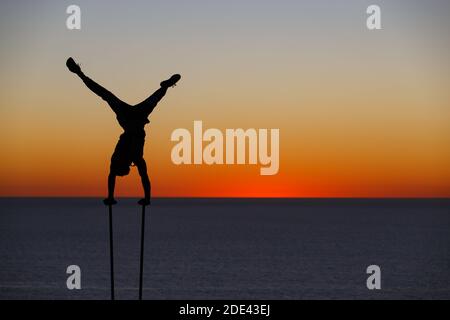 La JOLLA, KALIFORNIEN. 27. November 2020. Ein Outddor Turner macht einen Handstand mit dem Sonnenuntergang hinter ihm am Torrey Pines Gliderport oberhalb von Black's Stockfoto