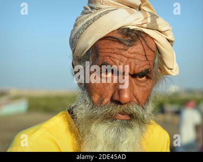Stern-aussehender bärtiger turbanierter alter Inder mit eingehüftem Gesicht und tiefen Falten auf der Stirn starrt auf die Kamera. Stockfoto