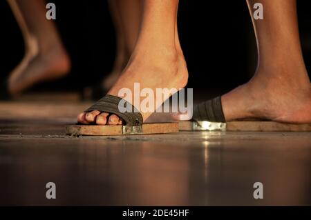 Bein einer Frau trägt Tanzschuhe aus Holz, handgemachte Sandalen aus Holz, Lichter auf Holzbühne Stockfoto