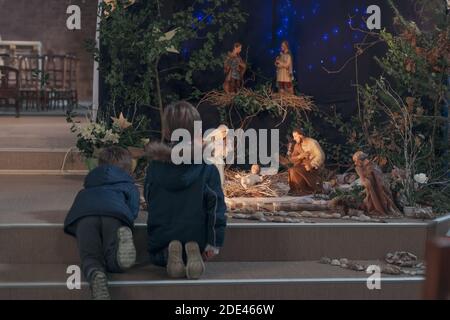 Kinder schauen sich die weihnachtskrippe mit Joseph Mary und Small an Jesus in einer Krippe Stockfoto