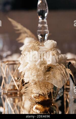 Blumenzusammensetzung auf dem Glasspiegeltisch. Dekoration im Hochzeitsrestaurant. Hochzeitsbankett. Stockfoto