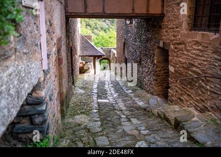 Das kleine mittelalterliche Dorf Conques in Frankreich. Es zeigt den Besuchern seine Abtei-Kirche und geclusterte Häuser gekrönt von Schieferdächern. Kreuzung der engen Straße Stockfoto