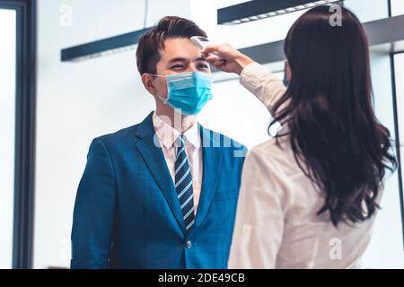 Geschäftsleute überprüfen die Temperaturmessung bereits vorher mit einem Infrarot-Digitalthermometer Arbeiten Stockfoto