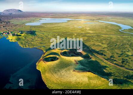 Luftaufnahme der Küste mit grünen Pseudo-Krater, Vulkankrater, kleine Häuser mit roten Dächern und Straße in vulkanischer Landschaft am Lake Myvatn Stockfoto