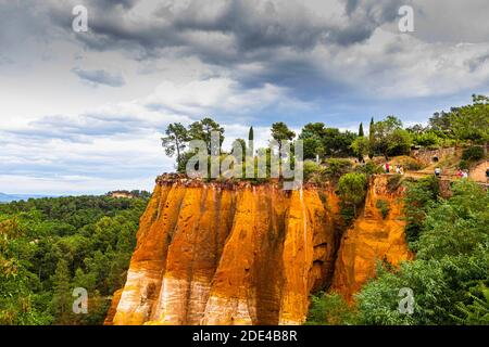 Steile Klippen im Naturpark der ockerfarbenen Klippen mit dramatischen Wolken oben, Roussillon, Luberon, Provence, Frankreich Stockfoto