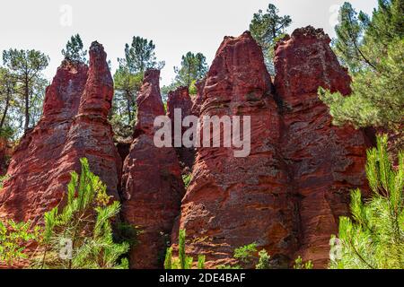 Rote pyramidenförmige Felsen im Naturpark der ockerfarbenen Felsen in Roussillon, Luberon, Provence, Frankreich Stockfoto