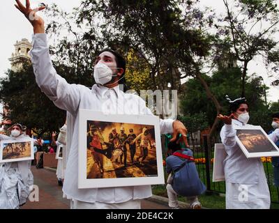 Ein Mann in Weiß, der ein Bild von den Märschen trägt, auf denen zwei junge Männer getötet wurden, und eine mobile Fotoausstellung mit dem Titel "La Exposición del Miedo" (Fear Showcase) zeigt, die die Erinnerung an Polizeigewalt, Verbrechen und Misshandlungen von Demonstranten in Lima - Peru vom 9. Bis 15. November 2020 sammelt Stockfoto