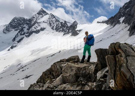 Schneefeld, Wanderer steht auf einem Stein, Abstieg vom Schönblichler Horn, Waxeggkees Gletscher, Weg vom Furtschaglhaus zur Berliner Huette, hoch Stockfoto