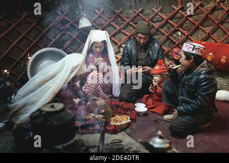 Ein Mann, zwei Frauen, zwei Kinder zu den Mahlzeiten, nomadische Kirgisen, Jurten, Bozai Gumbaz, Wachan-Korridor, Badakhshan, Afghanistan Stockfoto