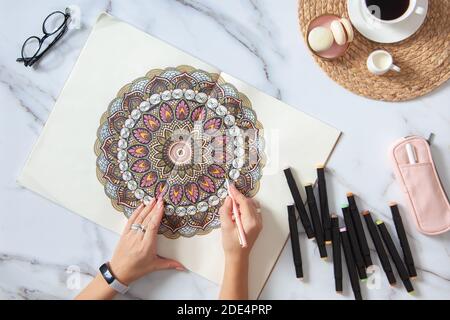 Frau Zeichnung und Färbung Mandala in Skizzenbüchern mit bunten Markierungen Beim Frühstück Stockfoto