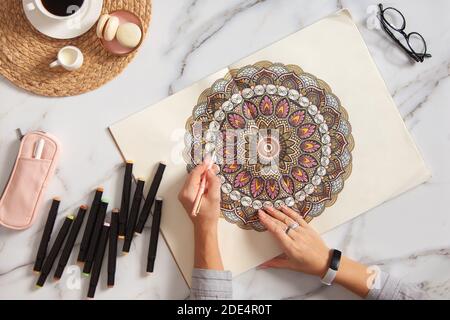 Frau Zeichnung und Färbung Mandala in Skizzenbüchern mit bunten Markierungen Beim Frühstück Stockfoto