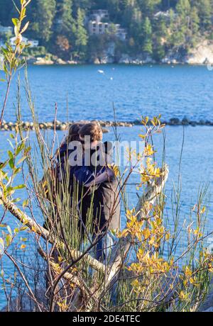 Blick auf das Paar, das an einem Felsenstrand in der Nähe des Ozeans steht und sich bei kaltem Herbstwetter umarmt. Reisefoto, Straßenansicht, verschwommen. Stockfoto
